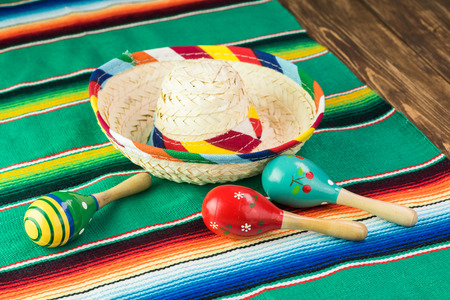 Close up of fiesta table with colorful wooden fiesta maracas, sombrero and traditional table runner.