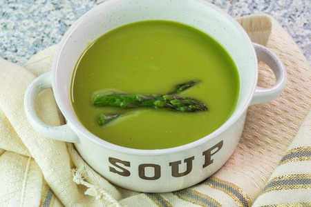 Close up of  pan with fresh homemade asparagus soup on kitchen table.の写真素材