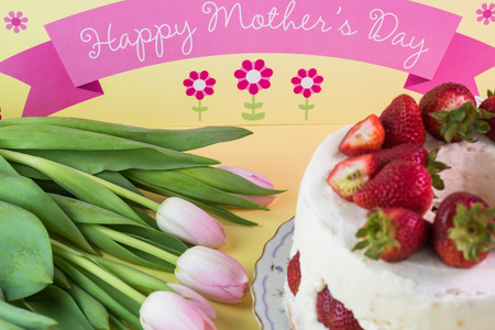 Close up of  colorful, creamy, delicious strawberry cake homemade for Mothers Day and tulips.