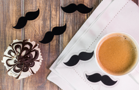 Close up of chocolate cupcake with mustache cupcake topper and cup of coffee.の写真素材