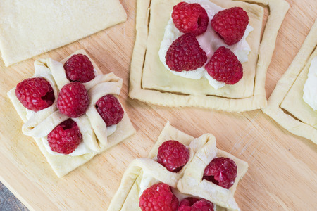 Close up of cutting board with berries cream cheese pastries with a flower shape.の写真素材
