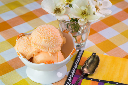 Close up of ice cream bowl with orange sherbet on a table.の写真素材