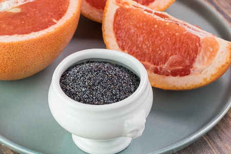 Close up of cut grapefruit, small bowl with organic poppy seed - ingredients for salad.の写真素材
