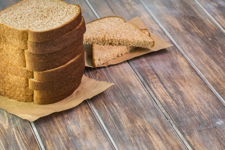 Close up of cut whole wheat bread on a wooden background.