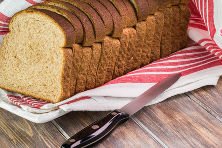 Close up of cut whole wheat bread on a wooden background.