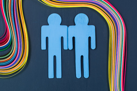 Homosexual symbol stylized gay couple and colorful rainbow paper on a wooden background.の写真素材