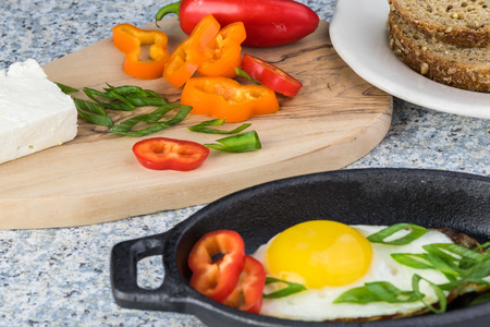 Close up of table with breakfast : fried egg, feta, fresh vegetables.の写真素材