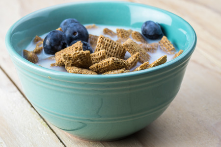 Close up of bowl with wheat cereal, blueberries and milk for breakfast.