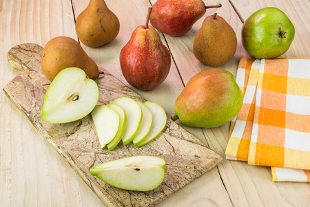 Close up of table with assorted pears and slices of pear on a cutting board.の写真素材
