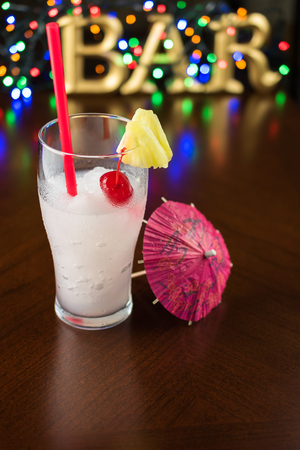 Close up of glass of frozen pina colada cocktail garnished with cherry and pieces of pineapple.の写真素材