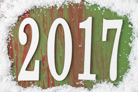 Background New 2017 Year with numbers, snow frame on a green wooden board.の写真素材