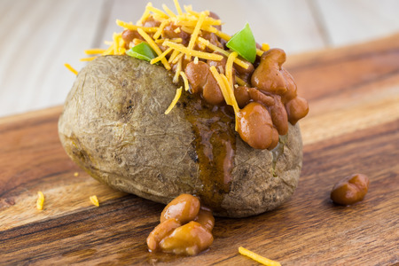 Close up of  loaded baked potato with  beans on a cutting board.の写真素材
