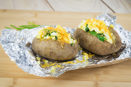 Close up of loaded baked potatoes with eggs, spinach, cheese.の写真素材