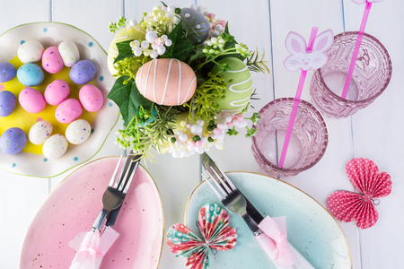 Close up of table decorated with flower egg centerpiece, egg shaped plates for Easter celebration.