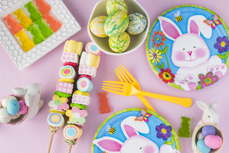 Top view of children party table decorated with bunny figurine, eggs, candies  for Easter...