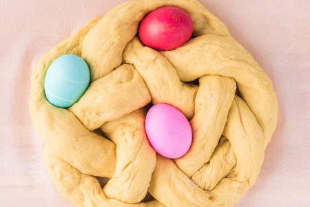 Close up of unbaked Easter bread with  colorful eggs on parchment paper.の写真素材