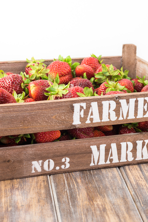 Close up of farmers crate with ripe strawberries on a wooden background.の写真素材