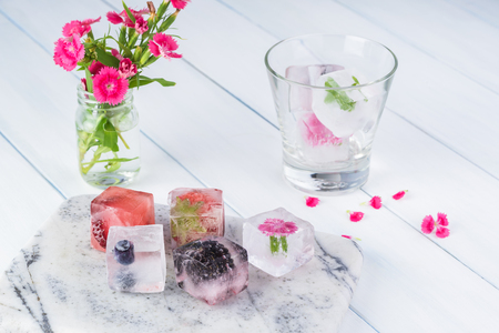 Ice cubes with berries on a cutting board and in a glass.の写真素材