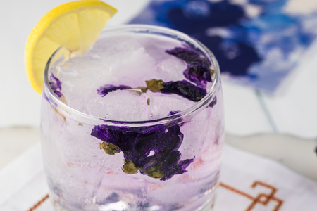 Close up of glass with vodka tonic cocktail with mallow blossom flowers.の写真素材