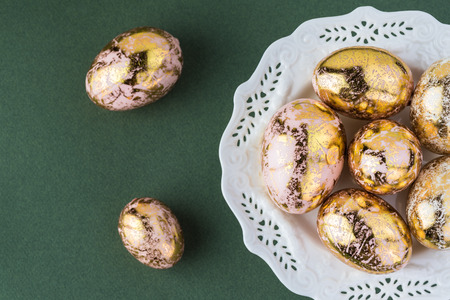 Top view of decorative easter eggs on a plate on a green background.