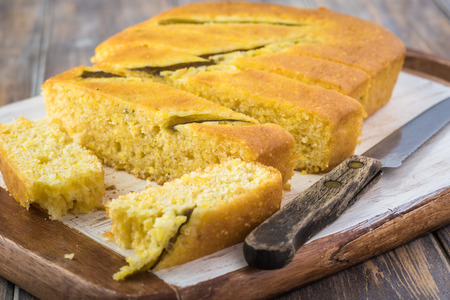 Close up of fresh baked cut hatch chili pepper cornbread on a cutting board.