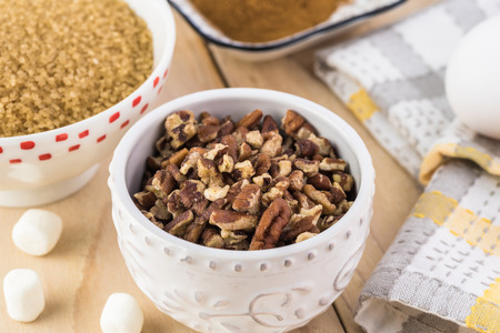 Cloase up of ingredients for sweet potato casserole - bowl with pecans, brown sugar on a table,