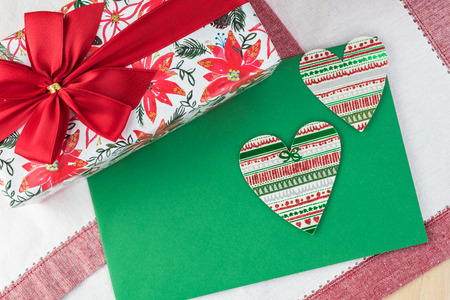 Wrapping candy box in Christmas paper, decorated with red bow  on woden  background - gift for Christmas. Greeting card concept.の写真素材