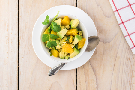 Close up of bowl with orange avocado salsa on wooden background.の写真素材