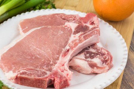 Close up of raw pork chops on a plate for roasted pork chops with avocado orange salsa.の写真素材
