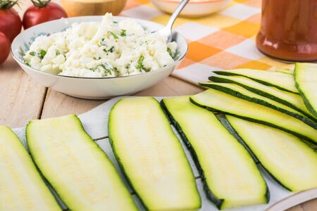 Cut zucchini and bowl with mixed two chesees - ricotta and feta and cut fresh basil.の写真素材