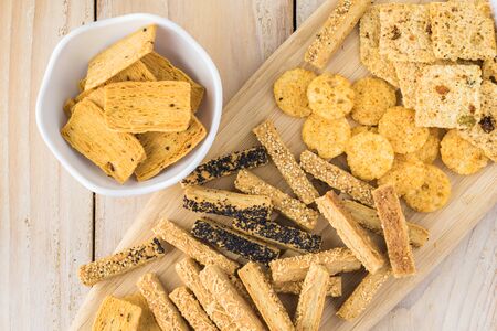 Assorted cheese sticks and cheese srisps on a cutting board.