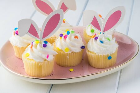 Close up of egg shaped plate with vanilla cream mini cup cakes decorated  for Easter celebration.