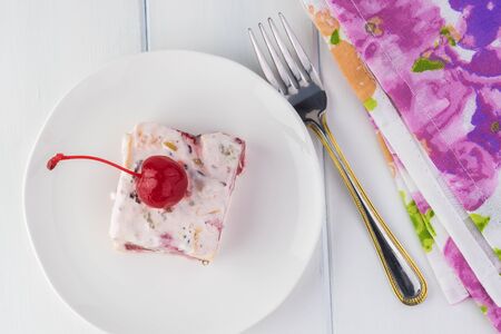 Piece of frozen fruit salad decorated with  cherry.