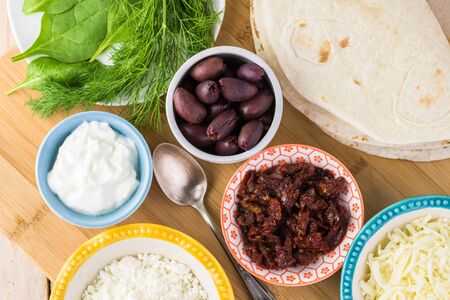 Ingredients for mediterranean style quesadillas - bowl with feta cheese, sun dried tomatoes, kalamata olives, yorgut, fresh dill, tortillas.の写真素材