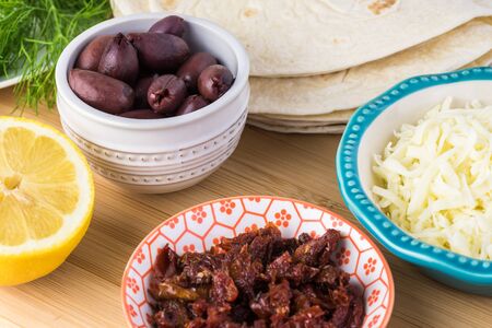 Ingredients for mediterranean style quesadillas - bowl with mozzarella cheese, sun dried tomatoes,...