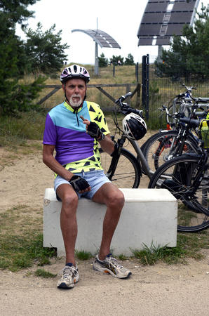 Elder cyclist with colorful clothes eats a snack sitting and relaxes at the border between Germany and Poland on Usedomの写真素材