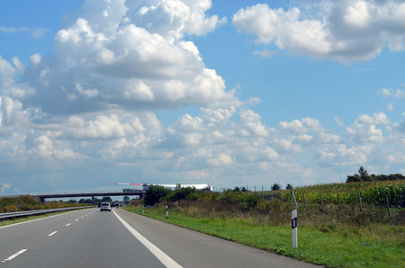 One wing of a blade for a wind turbine on a bridge over a highway in Germany transported by a heavy haulageの写真素材