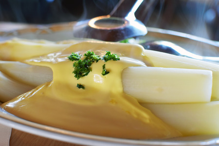 Fresh white asparagus from Beelitz (Germany), which is still steaming, on a plate with sauce hollandaise and asparagus tongsの写真素材