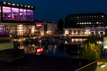 Berlin, Germany - July 27, 2018: Night shot of a harbor on the Teltow Canal in Berlin-Tempelhof with boats, old warehouses and cranes. There are also restaurants with colorful lights.のeditorial素材