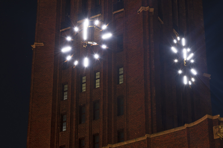 Night shot of a lit clock at the tower from a historic industrial building in Berlin-Tempelhof.の写真素材