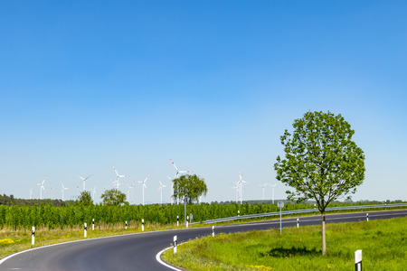Many wind turbines for environmentally friendly energy production on a field in Germany. In the foreground you can see the driveway to a highway.の写真素材
