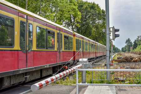 Berlin, Germany - July 22, 2018: Scene at a Berlin railroad crossing with closed barrier, which is passed by a train of the company Deutsche Bahn.のeditorial素材
