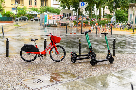 Berlin, Germany - July 13, 2019: Parked rental bicycles and rental scooters on a square in downtown...