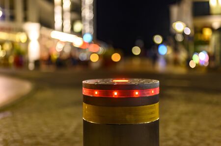 A retractable bollard with a red warning light as a barrier to a pedestrian area at night in Bansin,...