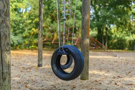 Children's playground in Germany with a tire swing and a climbing frame in the background.の写真素材