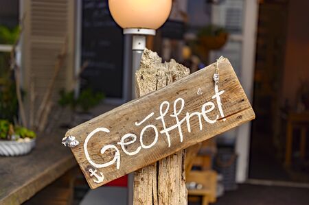 Board on a wooden post in front of a shop with the wordの写真素材