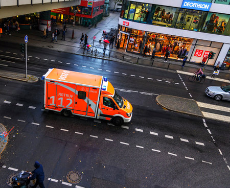 Berlin, Germany - October 5, 2019: Ambulance of the fire department in a busy shopping street in Berlin-Steglitz in rainy weather during a mission drive.のeditorial素材