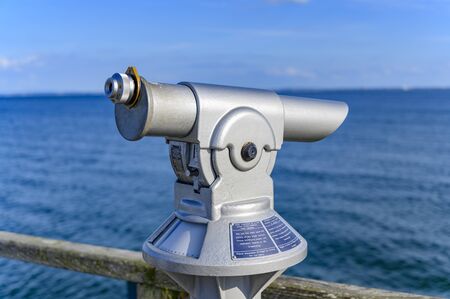Telescope with coin slot on the pier in Bansin on the island of Usedom in Germany. Sea and sky are...