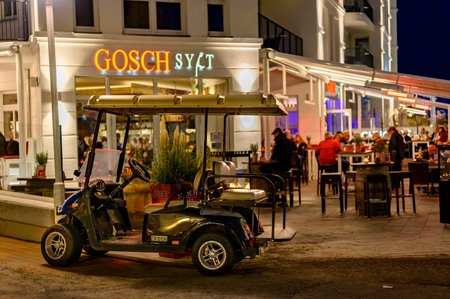 Bansin, Germany - September 14, 2019: Fully occupied tables and chairs at a restaurant in evening. In the foreground you can see a golf cart for bringing guests to their hotel.のeditorial素材