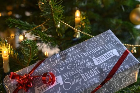 Packed Christmas present and decoration with a christmas tree in the background.の写真素材